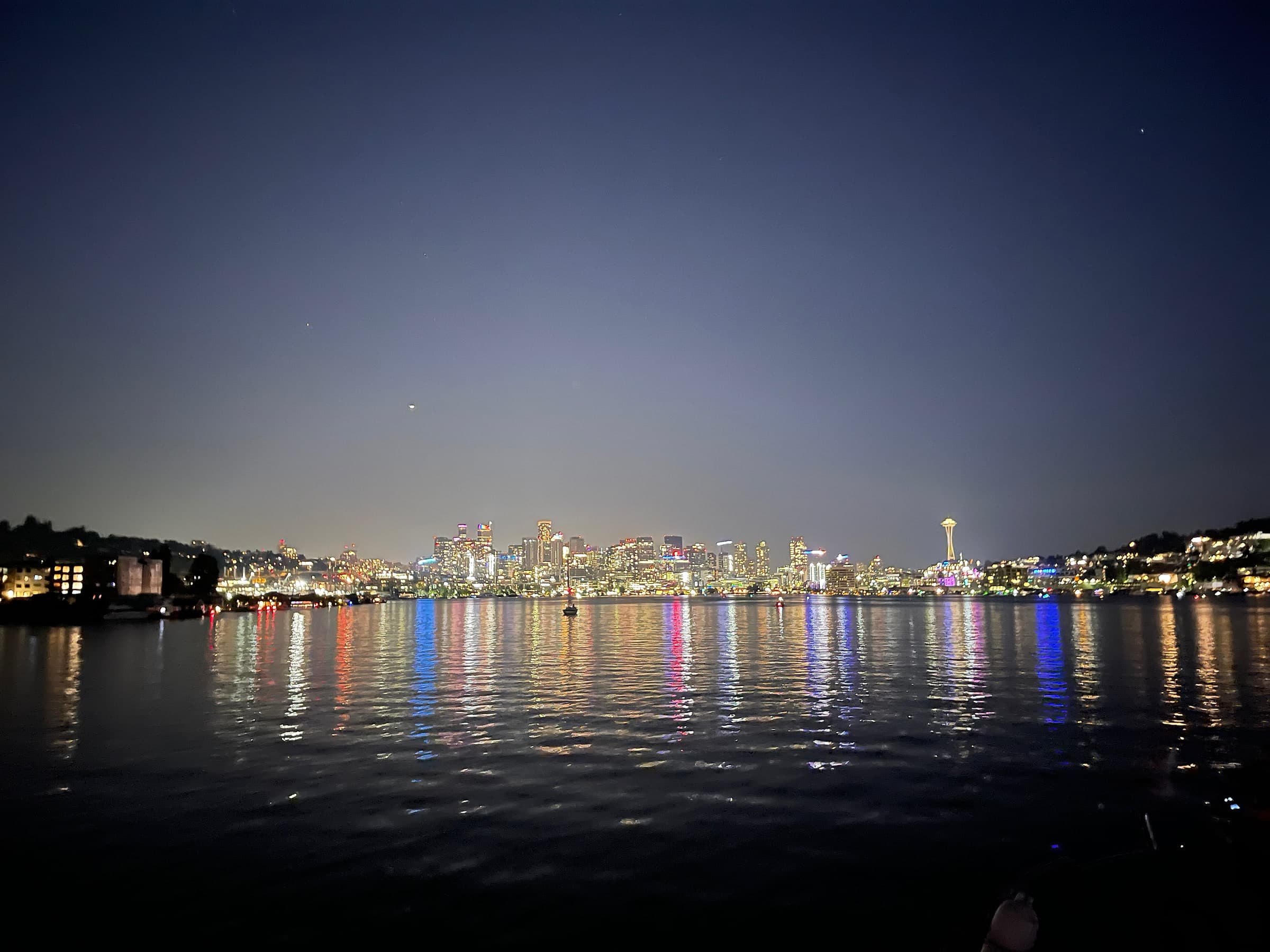 The Seattle skyline and Space Needle at night, reflected across Lake Union