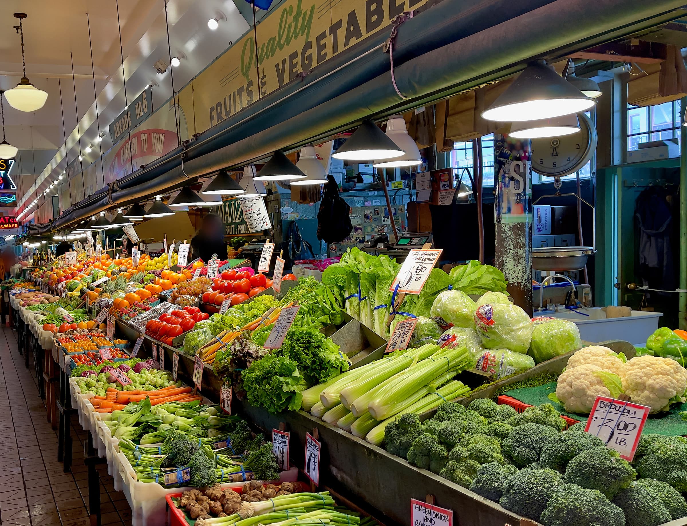 Produce stalls under the neon signs of the Pike Place Market arcade